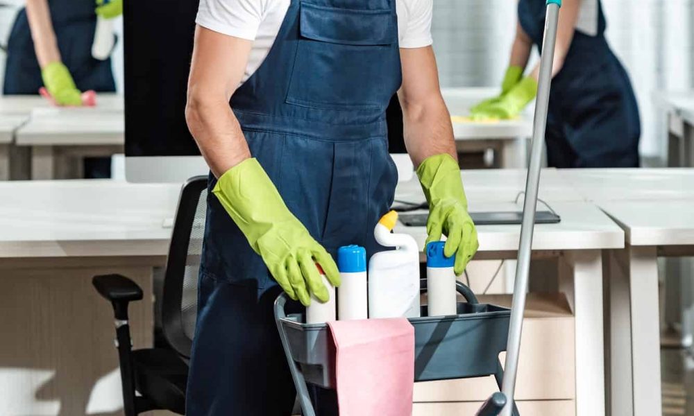 young-cleaner-standing-near-cart-with-cleaning-supplies.jpg
